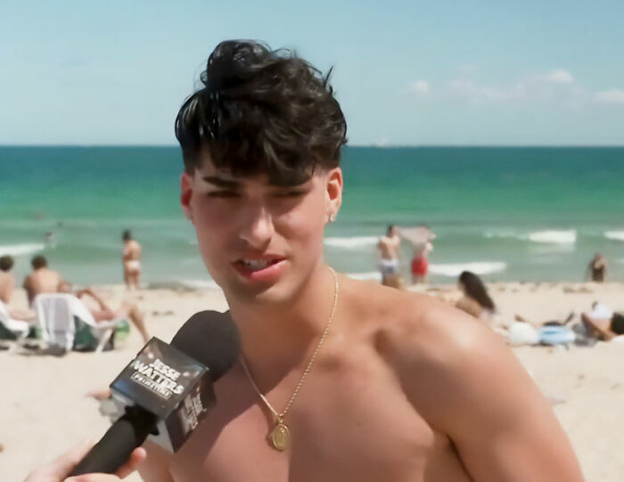 Young man on a beach being interviewed for a viral video about spring breakers answering news questions vapidly.