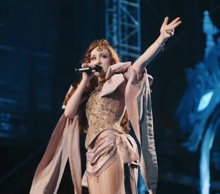 Chappell Roan se apresentando no palco vestindo fantasias complexas durante um festival antes de ser banido por incidente com segurança.