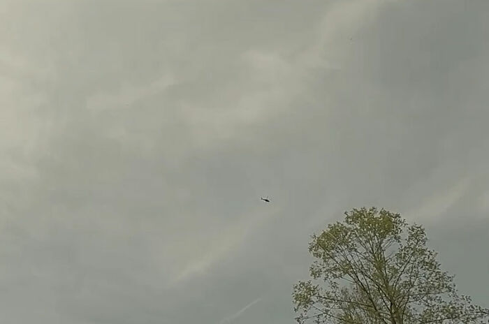 Helicopter flying above a tree under cloudy sky in search related to middle school secretary case.