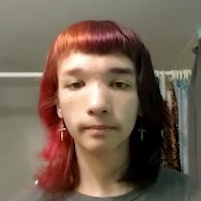 Young person with red and black hair and cross earrings, related to bodies of father and daughter found on gravel road news.