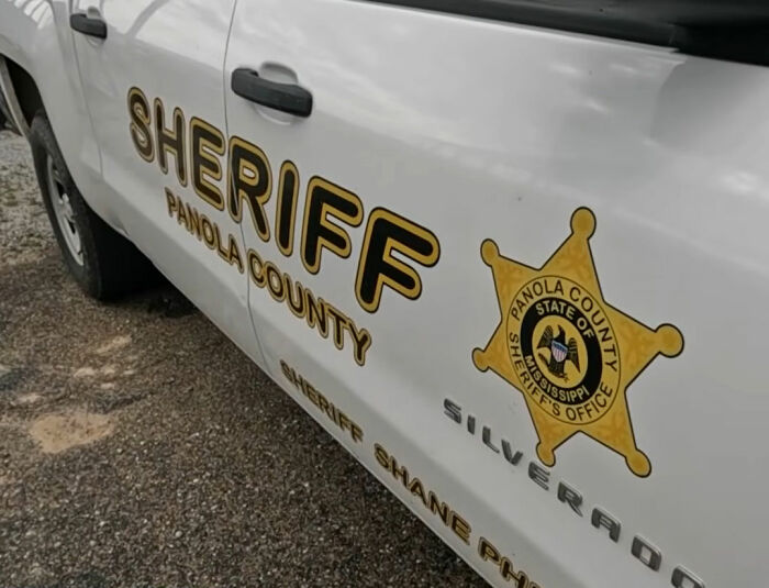Panola County sheriff vehicle parked on gravel road investigating bodies of father and daughter found after PS5 marketplace meeting.