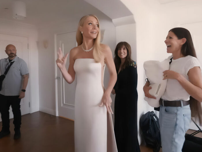 Gwyneth Paltrow in a sleek Oscars dress, surrounded by team members, revealing details behind a risky fashion malfunction.