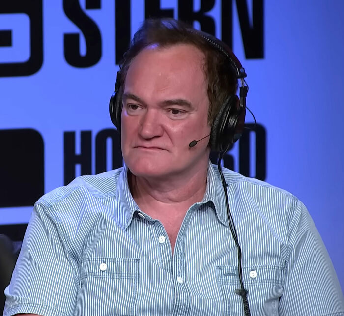 Quentin Tarantino wearing headphones and a striped shirt, responding to fans in a studio setting.