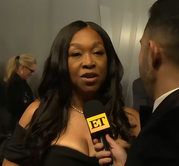 Shonda Rhimes speaking to a reporter during an interview, discussing Oscars' In Memoriam tribute decision.