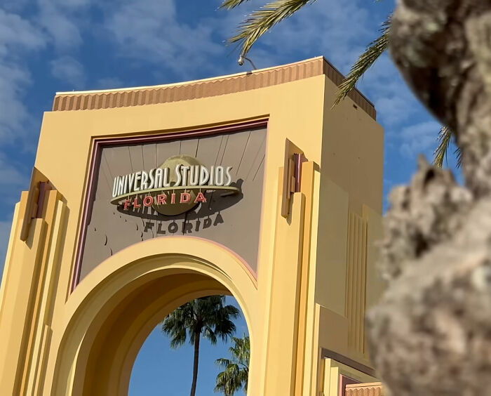 Universal Studios Florida entrance arch with palm trees and blue sky on a sunny day at the theme park.