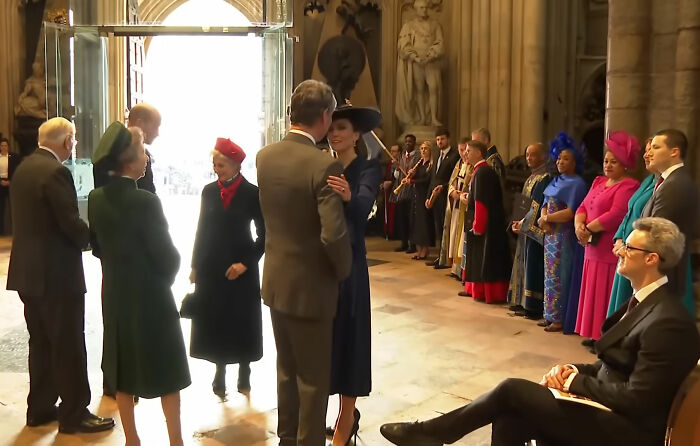 Prince William in dark suit speaking with family during largest royal gathering since Andrew's arrest in a grand hall.