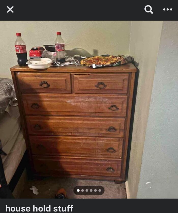 Wooden dresser with worn drawers, cluttered with soda bottles, pizza, and miscellaneous items in an unhinged Facebook Marketplace listing.