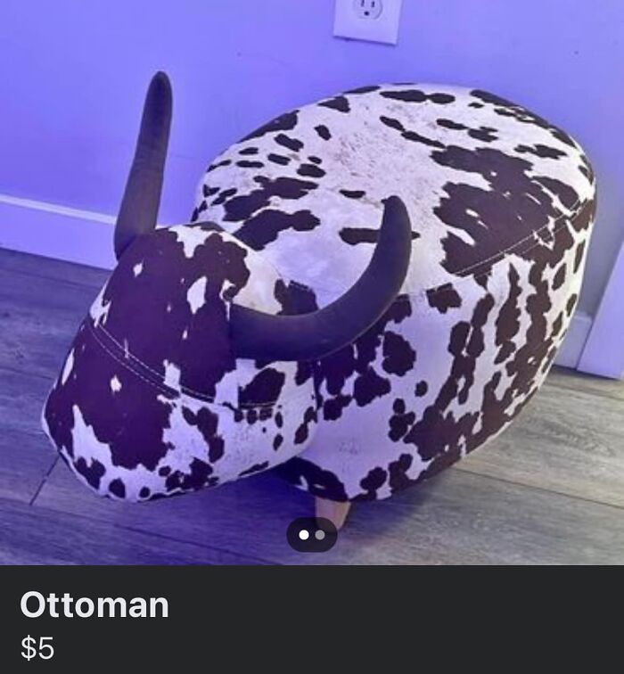 Cow print ottoman with horns on wooden legs listed on Facebook Marketplace, an unhinged pic that requires a double take to understand.
