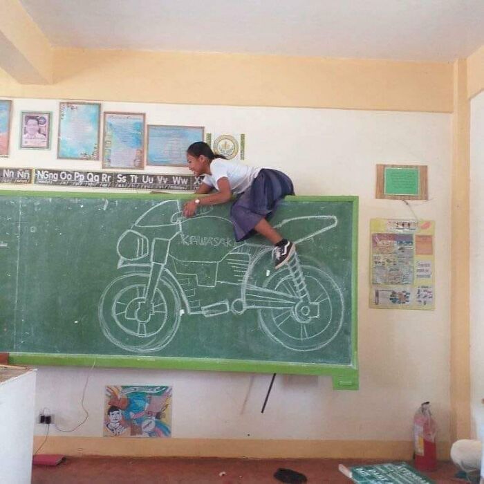 Child creatively posing as if riding a chalkboard motorcycle, showcasing one of the hilarious and creative poses pulled off perfectly.