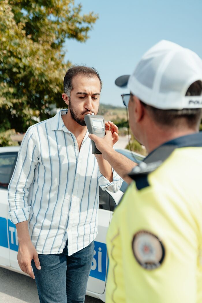 A man blowing into a breathalyzer held by a police officer during a roadside test, illustrating life destroyed in an instant.