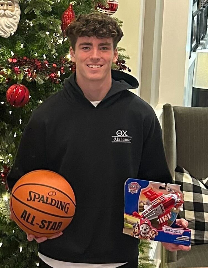 Jovem estudante do Alabama segurando basquete e brinquedo, sorrindo em frente à árvore de Natal decorada durante a temporada de férias. Jovem estudante do Alabama segurando basquete e brinquedo, sorrindo em frente à árvore de Natal decorada durante a temporada de férias.