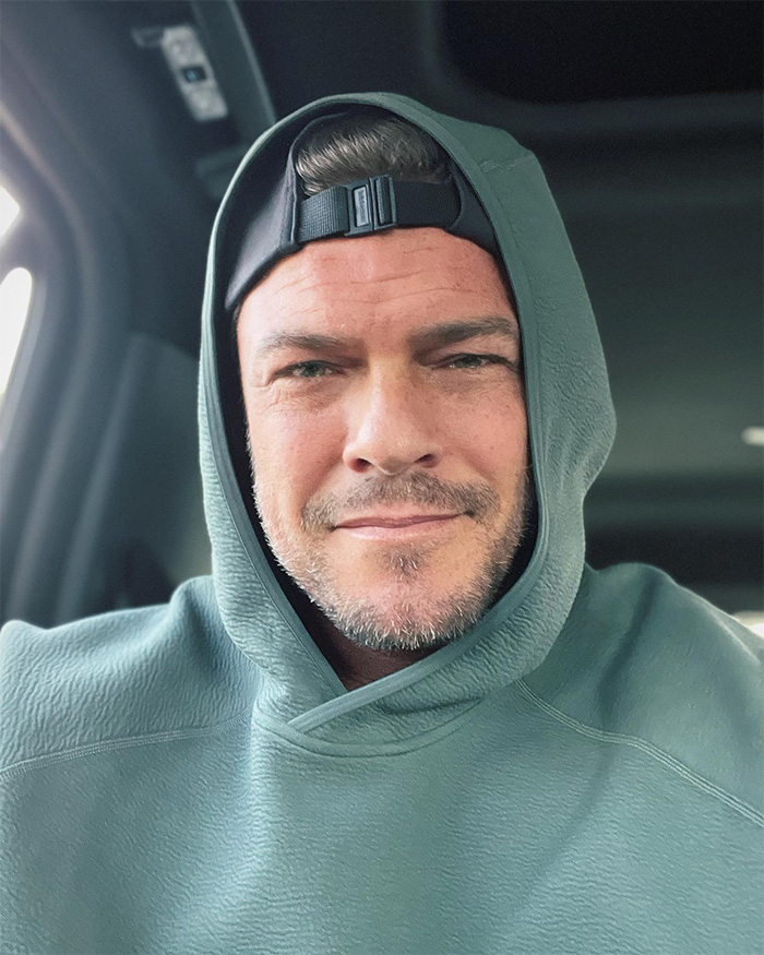 Alan Ritchson in a green hoodie and black cap, sharing bodycam footage details of a brutal neighbor confrontation.