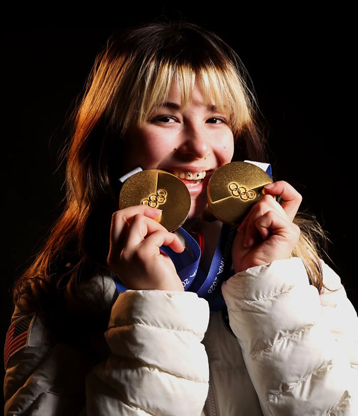 Olympic hero Alysa Liu smiling and holding two gold medals, celebrating her achievements in figure skating.