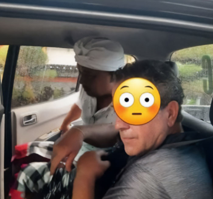American tourist with shocked emoji face inside vehicle after Bali shutdown arrest by local authorities.