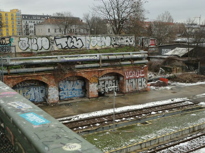 Abandoned urban site with graffiti-covered walls and train tracks, perfect for terrifying urban explorers seeking adventure.