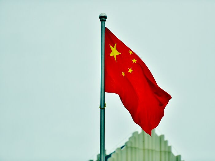 Chinese flag waving on a pole, illustrating cultural things people thought were normal until visiting other countries.