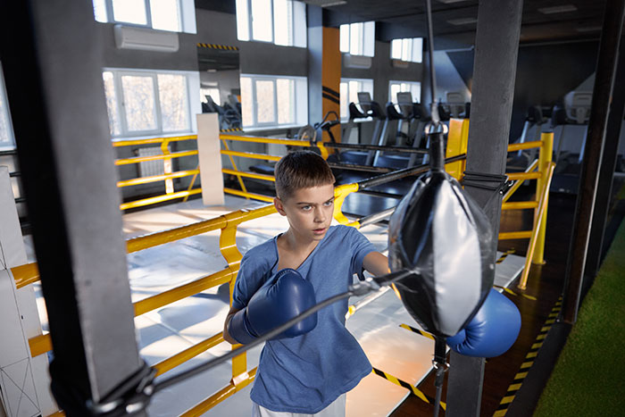 Young boy training with boxing gloves in gym, highlighting uncertain boxing match and family conflict over dogs.