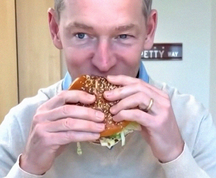 Man with wedding ring eating a sesame seed burger indoors illustrating epic PR fails in advertising campaigns.