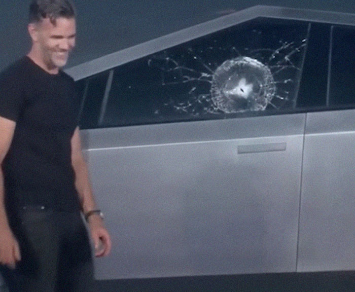 Man smiling next to a car with a shattered window, illustrating one of the epic PR fails that surprised many.