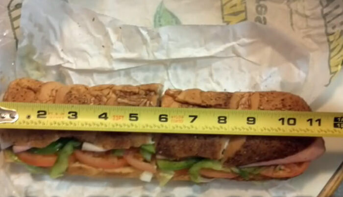 Subway sandwich being measured with a tape, highlighting an epic PR fail related to food portion claims.