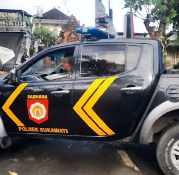 Black police truck with yellow markings parked near a temple during Bali shutdown enforcing consequences for public outings.