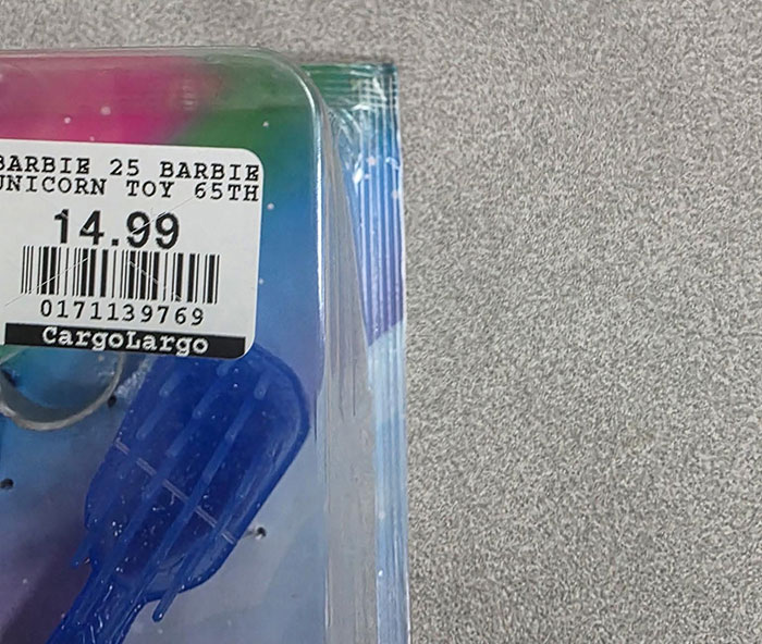 Close da embalagem da Barbie mostrando uma etiqueta de preço e parte da boneca com conteúdo escondido dentro da embalagem. Close da embalagem da Barbie mostrando uma etiqueta de preço e parte da boneca com conteúdo escondido dentro da embalagem.
