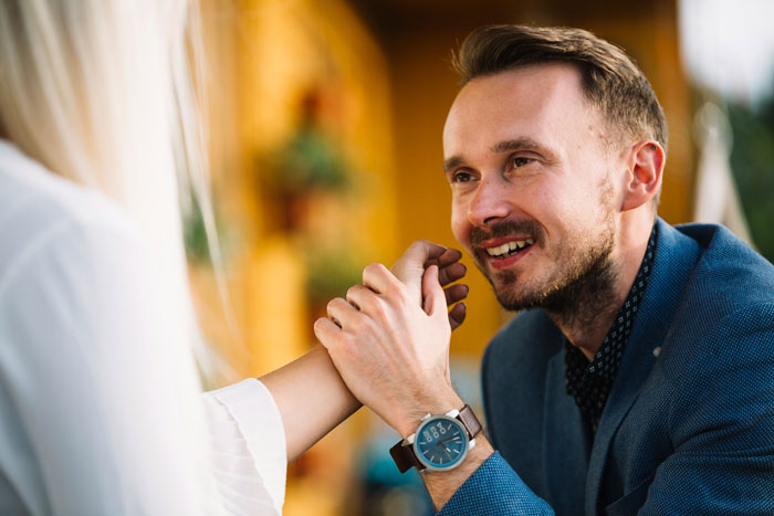 Man holding woman's hands intensely during a serious conversation about boyfriend demands and medical procedure veto.