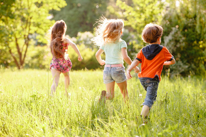 Three children running through a sunny grassy field symbolizing fatherhood dreams and family future hopes.