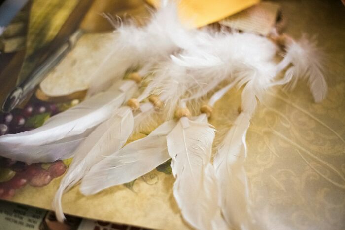 White feathers and wooden beads laid out on a patterned surface, reflecting creepy things found in old homes.