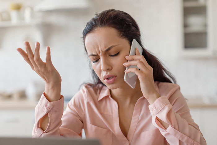 Woman frustrated on phone call, expressing anger in a bright modern kitchen, related to best friend fight mom situation.
