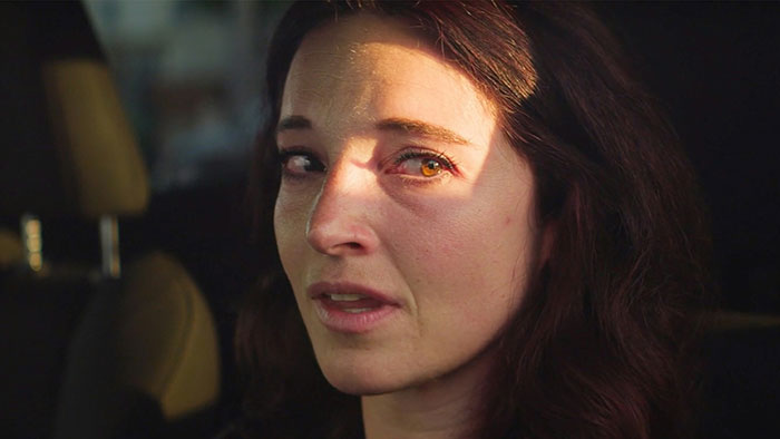 Woman with tearful eyes in low light, reflecting on romantic indifference and forgotten details about a cat.