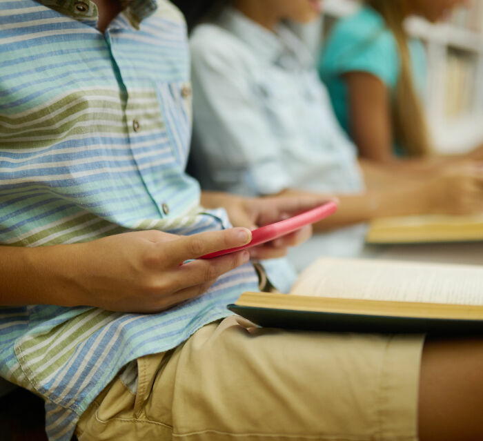 Student secretly filming in classroom with book open, highlighting a California teacher suspended after a bizarre act.