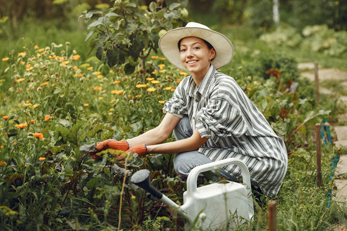 Young woman gardening outdoors, smiling while tending plants, reflecting a devoted girlfriend feeling like second best.