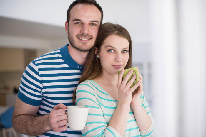 Young woman and man holding mugs at home, illustrating a 22-year-old imagining things and hearing voices before ER visit.