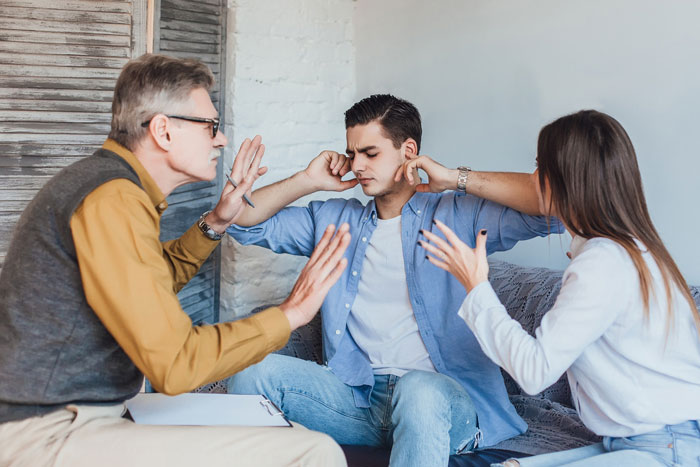Young man covering ears while parents argue about breaking family tradition getting dog at home.