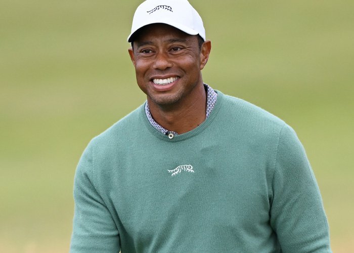 Tiger Woods sorrindo ao ar livre usando um boné branco e um suéter verde, relacionado à prisão e DUI no acidente na Flórida. Tiger Woods sorrindo ao ar livre usando um boné branco e um suéter verde, relacionado à prisão e DUI no acidente na Flórida.