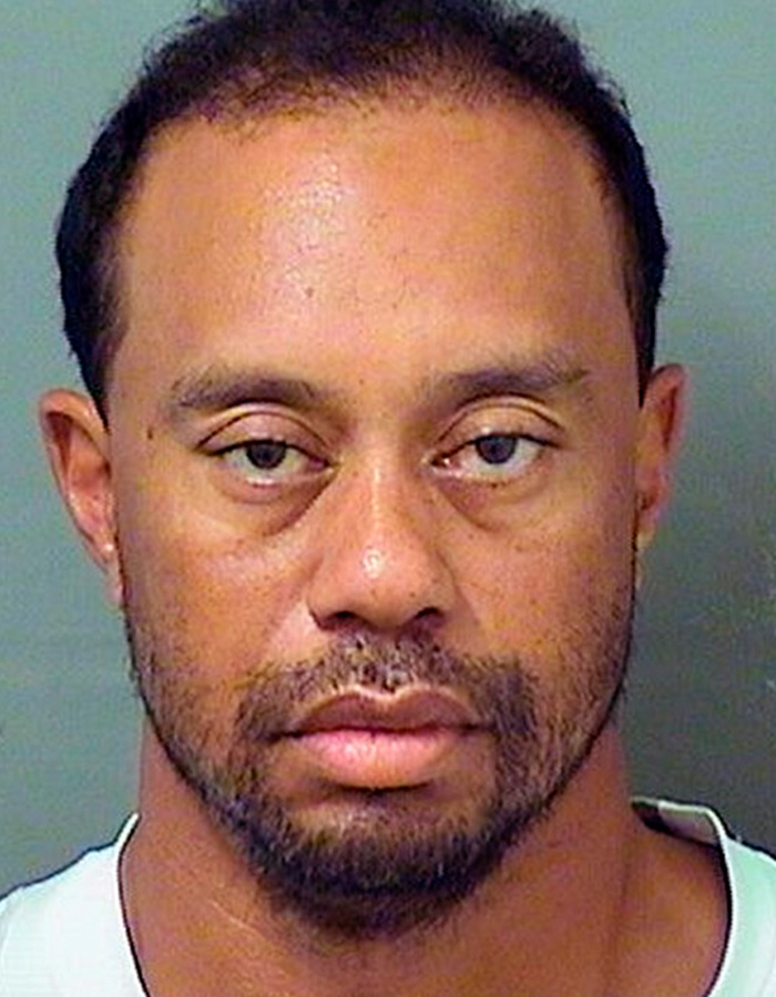 Foto de Tiger Woods após prisão por DUI após acidente de capotamento na Flórida, mostrando expressão séria e fundo neutro. Foto de Tiger Woods após prisão por DUI após acidente de capotamento na Flórida, mostrando expressão séria e fundo neutro.