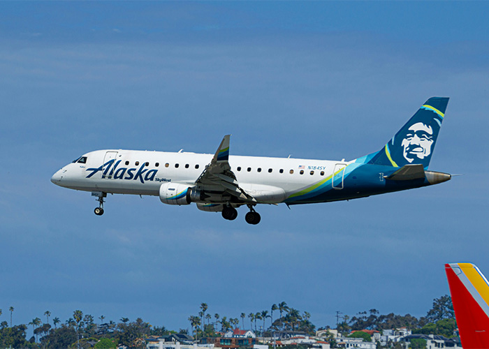Alaska Airlines plane in flight against clear sky, related to Brenda Song slamming airline for family seating issue. Alaska Airlines plane in flight against clear sky, related to Brenda Song slamming airline for family seating issue.