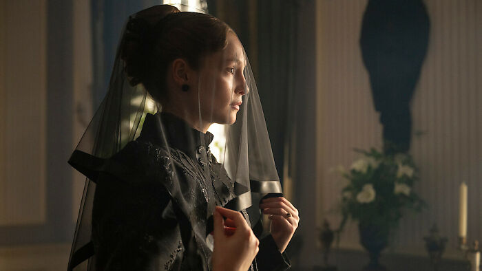 Woman in a black veil and dress, standing in a dimly lit room, symbolizing Bridgerton Season 5 controversy.