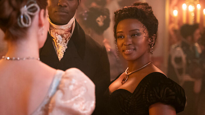 A Bridgerton Season 5 scene showing characters in period attire during an elegant ball, highlighting its controversial update.