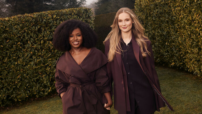 Two women smiling and holding hands outdoors, representing Bridgerton Season 5's big update and controversy.