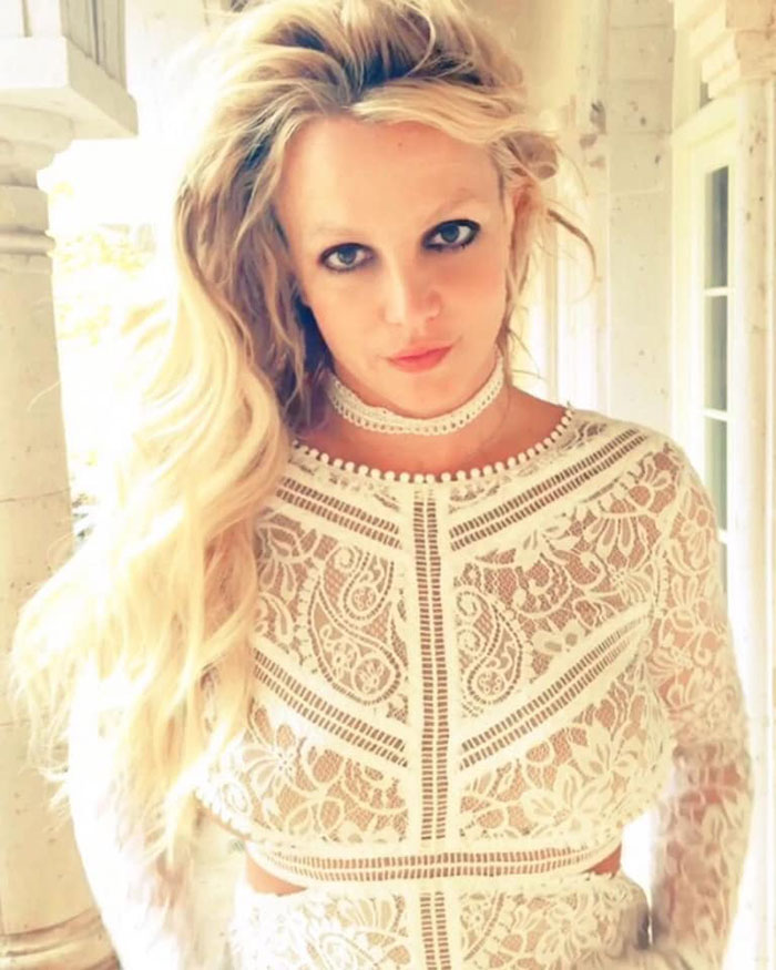 Britney Spears in a white lace outfit with long blonde hair, highlighting the heartbreaking reason underlying her arrest.