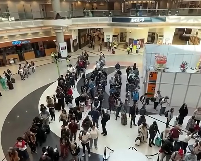 Crowded airport terminal showing passengers waiting in line with luggage, highlighting Brooklyn man’s reaction to ICE presence.