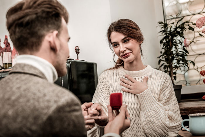 A man proposes with an engagement ring to a woman who looks hesitant, hinting at an entire proposal called off.