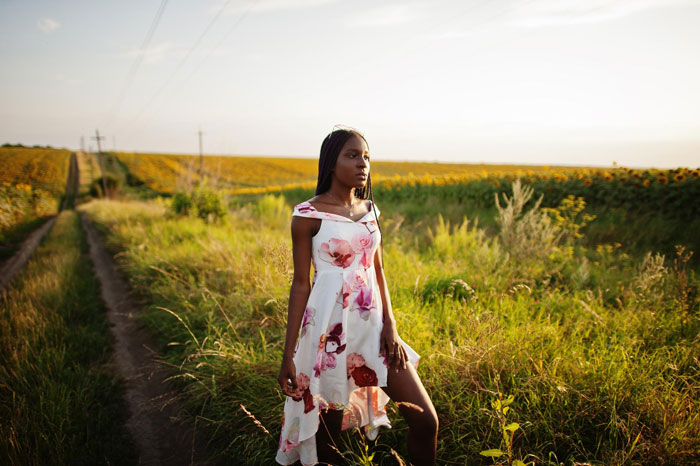 Young woman standing in a rural field, symbolizing brother inherited land money and family inheritance themes.