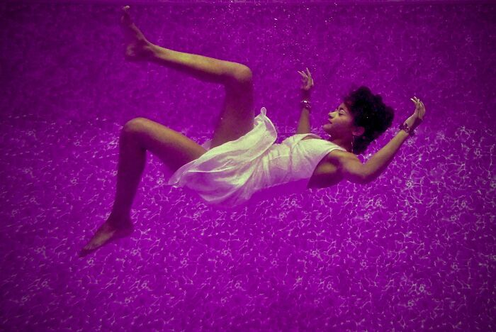 Woman in a white dress floating underwater in a pool, illustrating mind-blowing scientific facts visually.