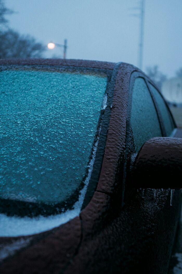 Car windshield and side window covered in ice on a cold winter morning during payback stories scenario.