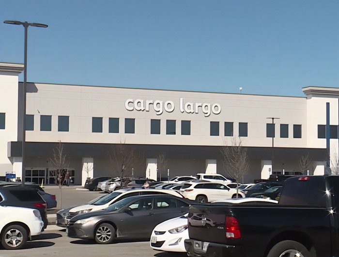 Prédio de armazém com muitos carros estacionados do lado de fora, relacionado a embalagens da Barbie revelando bonecas escondidas. Prédio de armazém com muitos carros estacionados do lado de fora, relacionado a embalagens da Barbie revelando bonecas escondidas.