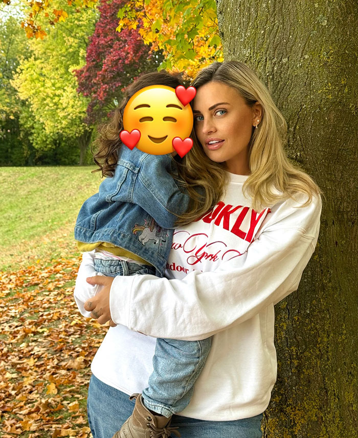 Woman holding child outdoors by a tree, relating to Britain's most hated woman and nose job diagnosis story.