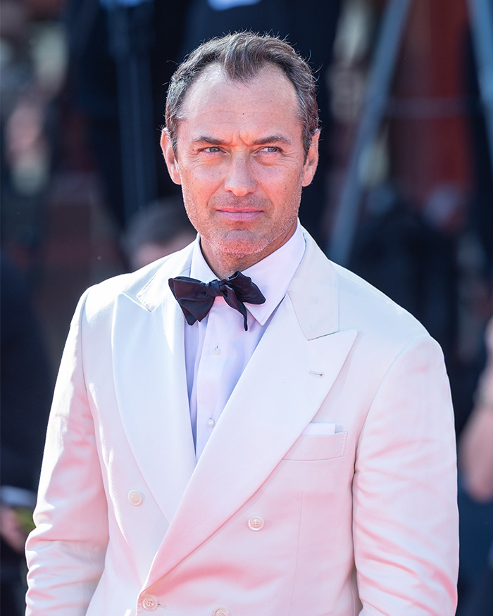 Man in a white tuxedo and black bow tie at a formal event, related to Chappell Roan backlash involving Jude Law's daughter. Man in a white tuxedo and black bow tie at a formal event, related to Chappell Roan backlash involving Jude Law's daughter.